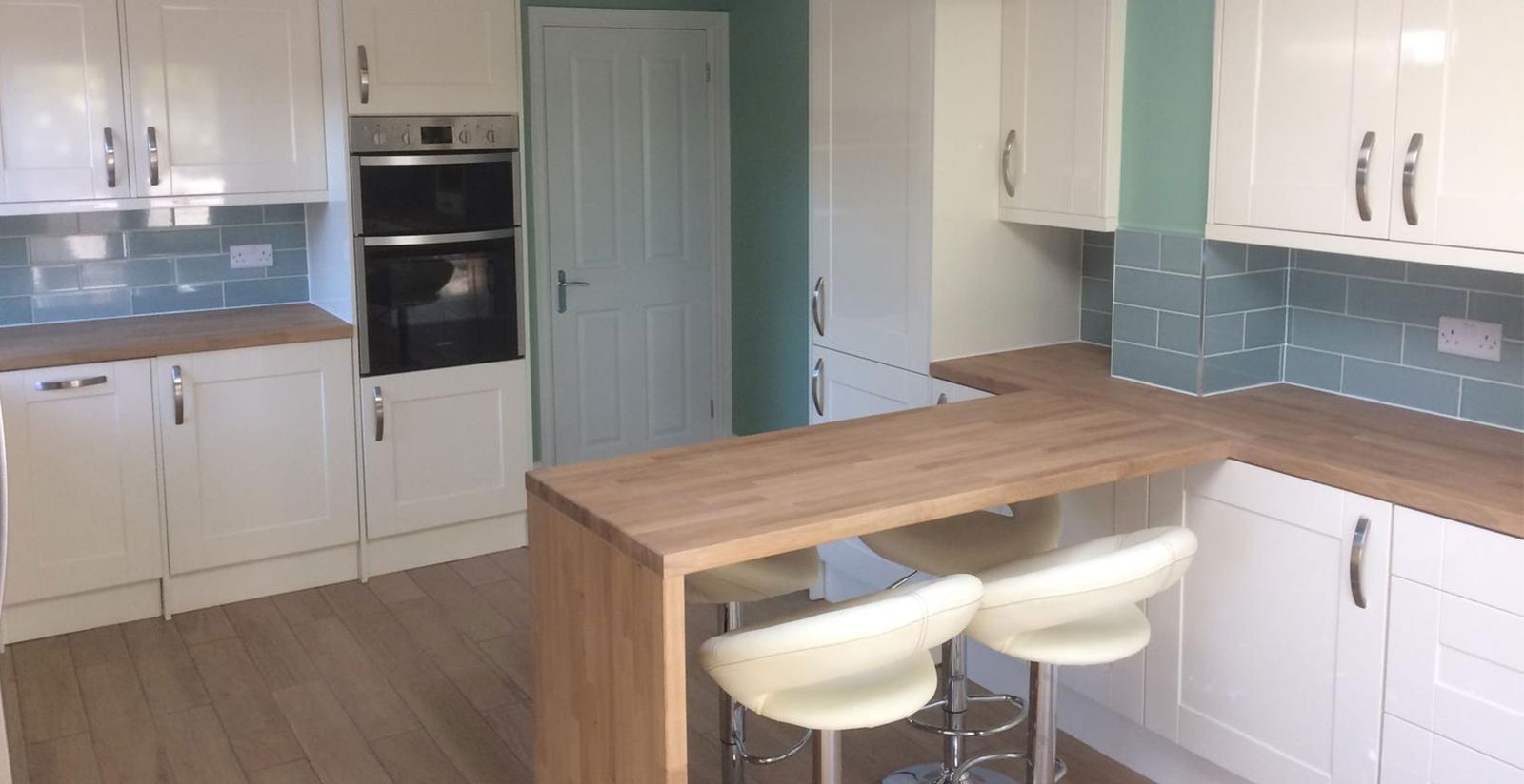 A bright white shaker kitchen with a wood breakfast bar