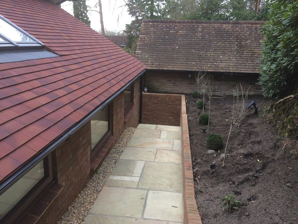 An Indian-sandstone patio and steps beside a rendered house